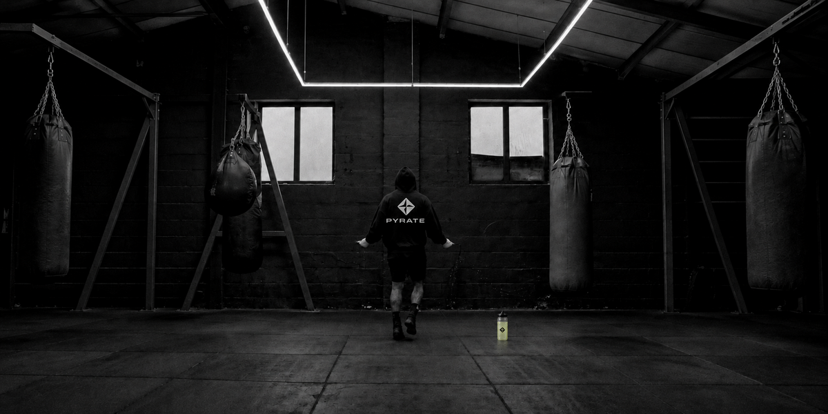 Athlete jumping rope in a gym with a PYRATE bottle nearby