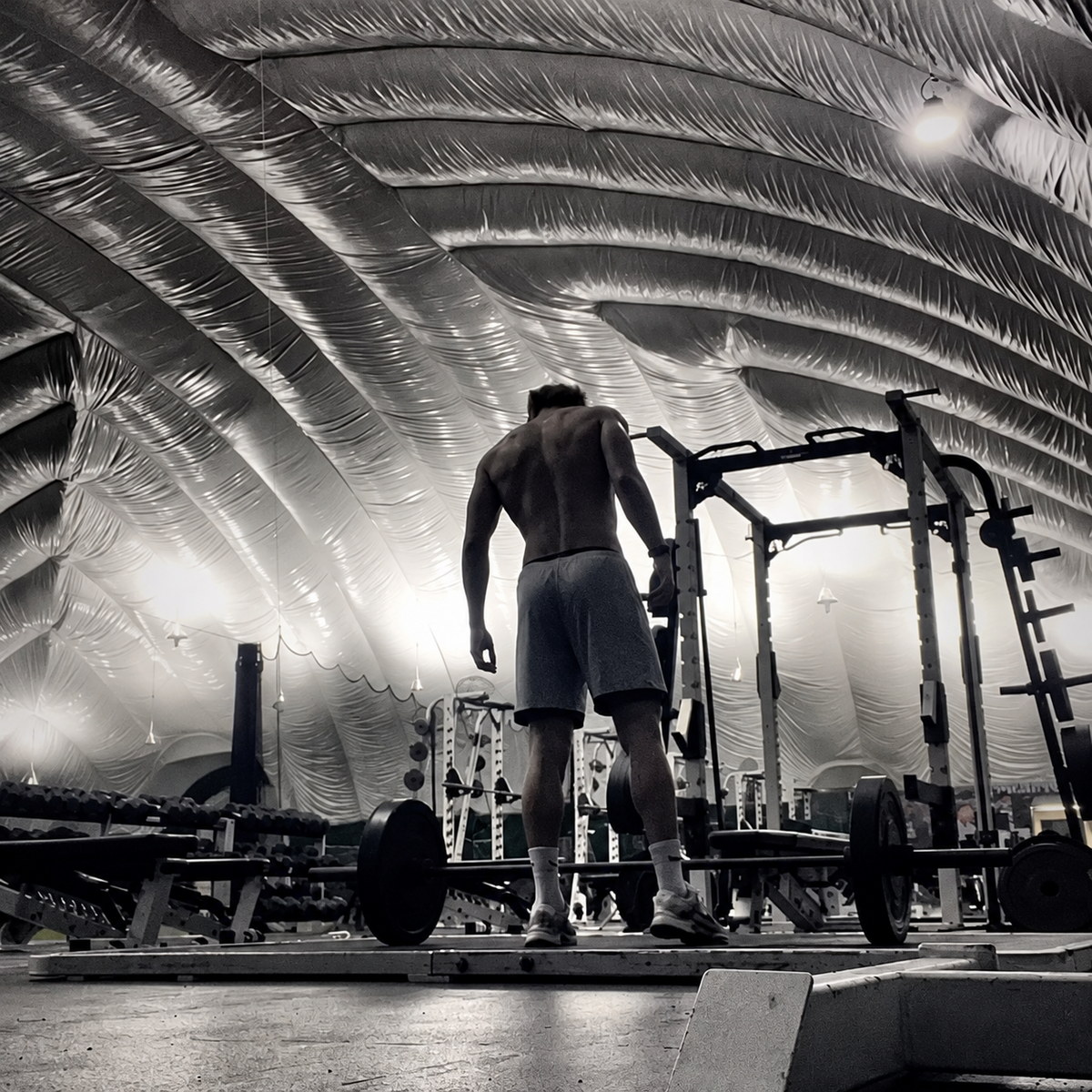 Lifter standing at a loaded barbell in a weight room